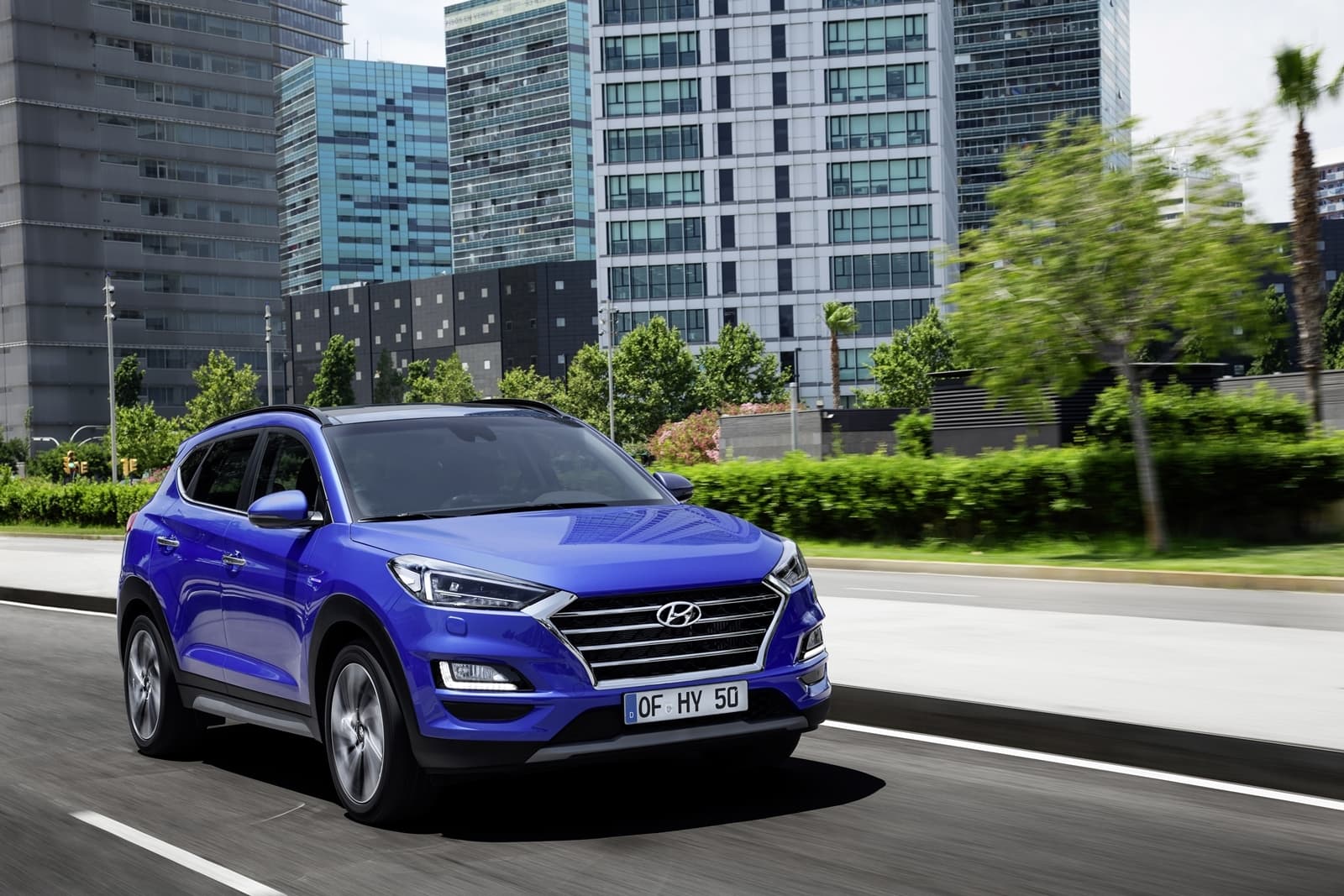 Vista dinámica del Hyundai Tucson en un entorno urbano, destacando su diseño delantero y lateral.