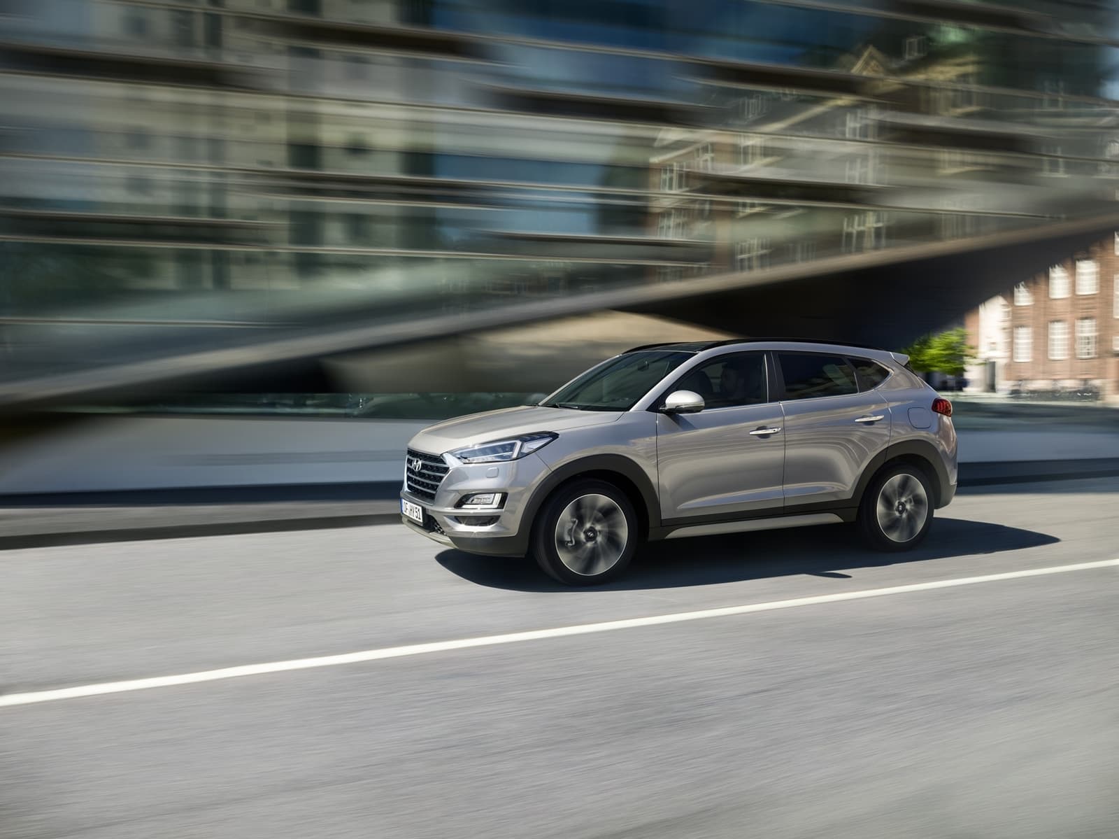 Vista dinámica lateral del Hyundai Tucson en movimiento, resaltando su diseño aerodinámico.