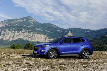 Vista lateral del Hyundai Tucson con montañas al fondo, destacando su diseño atlético.