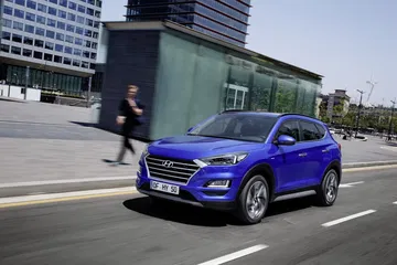 Vista dinámica del Hyundai Tucson en entorno urbano, color azul.