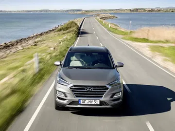 Vista dinámica del Hyundai Tucson en carretera, ángulo frontal y lateral