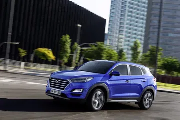 Vista dinámica lateral y delantera de un Hyundai Tucson en movimiento.