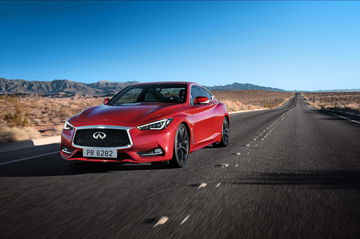 Vista dinámica del Infiniti Q60 en carretera, destacando su diseño lateral y frontal.