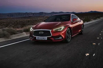 El Infiniti Q60 rojo muestra su elegancia y deportividad en una carretera al atardecer.