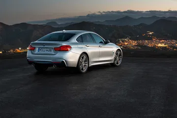 BMW Serie 4 capturado en una vista lateral y posterior con el crepúsculo de fondo.