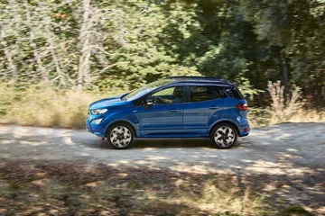 Ford EcoSport en movimiento por un entorno boscoso, mostrando su perfil lateral.