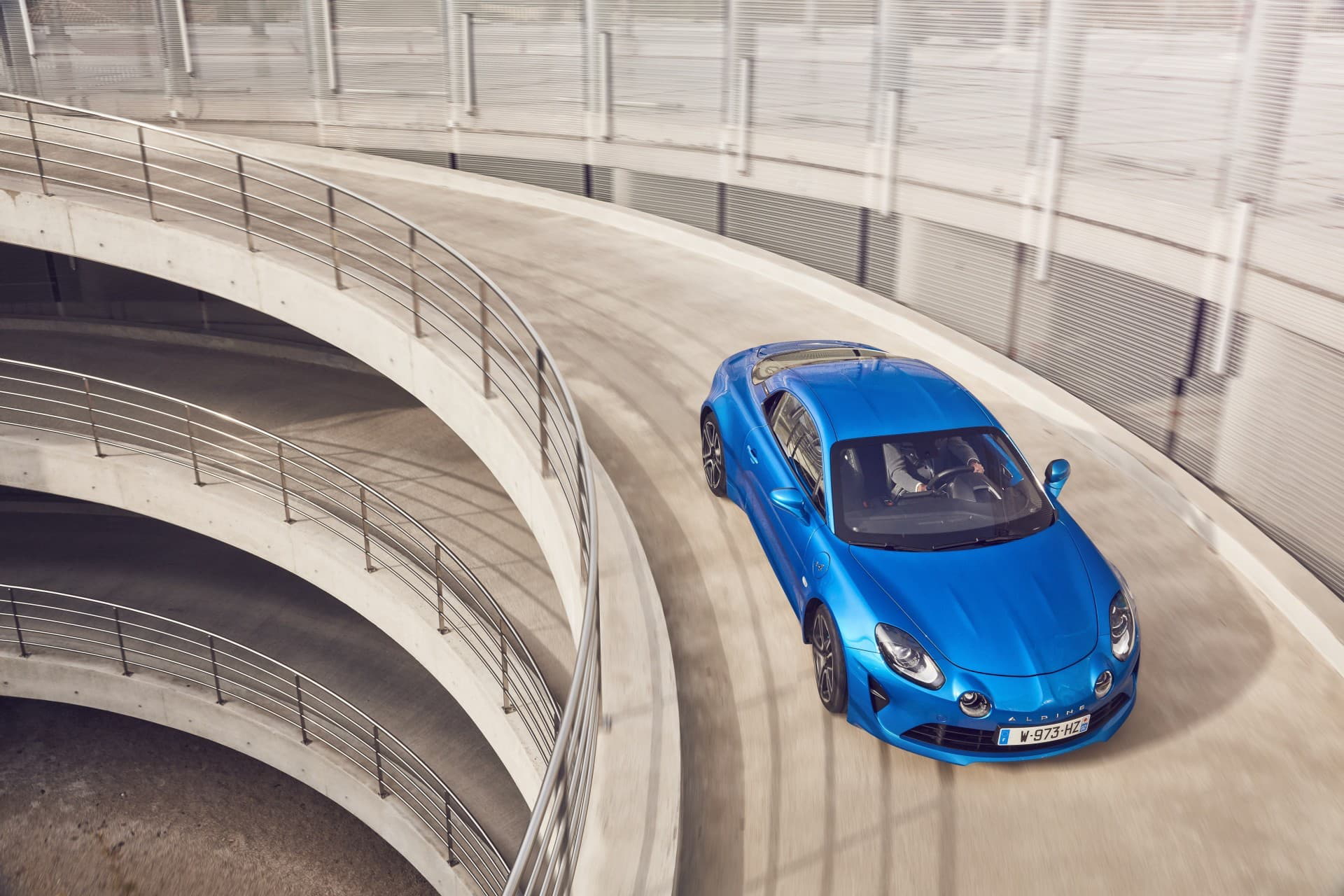 Vista aérea del Alpine A110 en color azul tomando una curva ascendente.