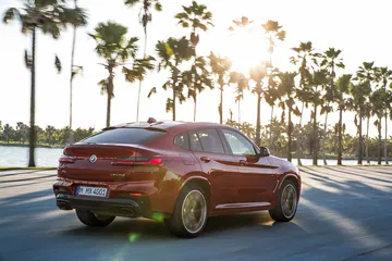 Vista lateral y posterior del BMW X4 en movimiento, iluminación natural.