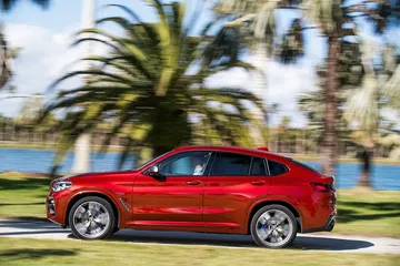 Vista dinámica del BMW X4 mostrando su perfil lateral en movimiento.