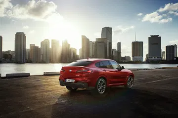 BMW X4 mostrando su línea lateral y zaga imponente frente a paisaje urbano.
