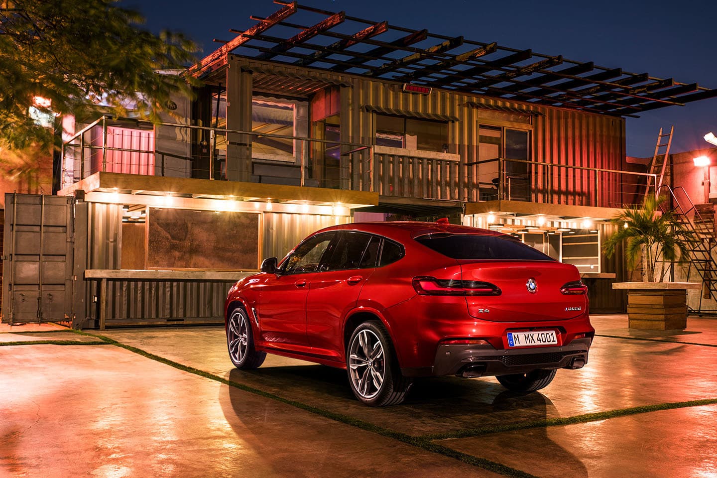 Vista nocturna realzando la silueta y diseño trasero-lateral del BMW X4.