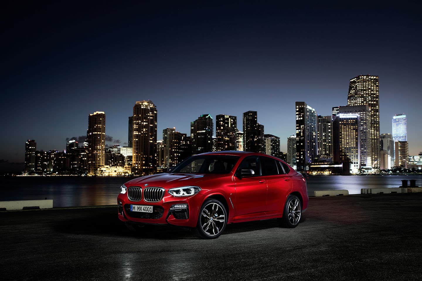 Vista angular delantera del BMW X4 en color rojo con skyline nocturno