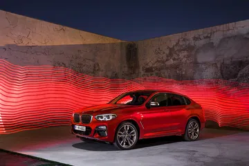 Vista lateral del BMW X4 iluminado de noche, mostrando el diseño aerodinámico.