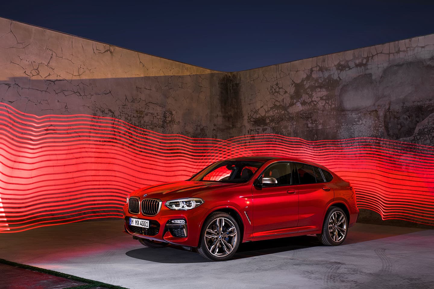 Vista lateral del BMW X4 iluminado de noche, mostrando el diseño aerodinámico.