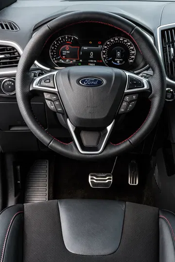 Vista del volante del Ford Edge enfocando emblema y controles.