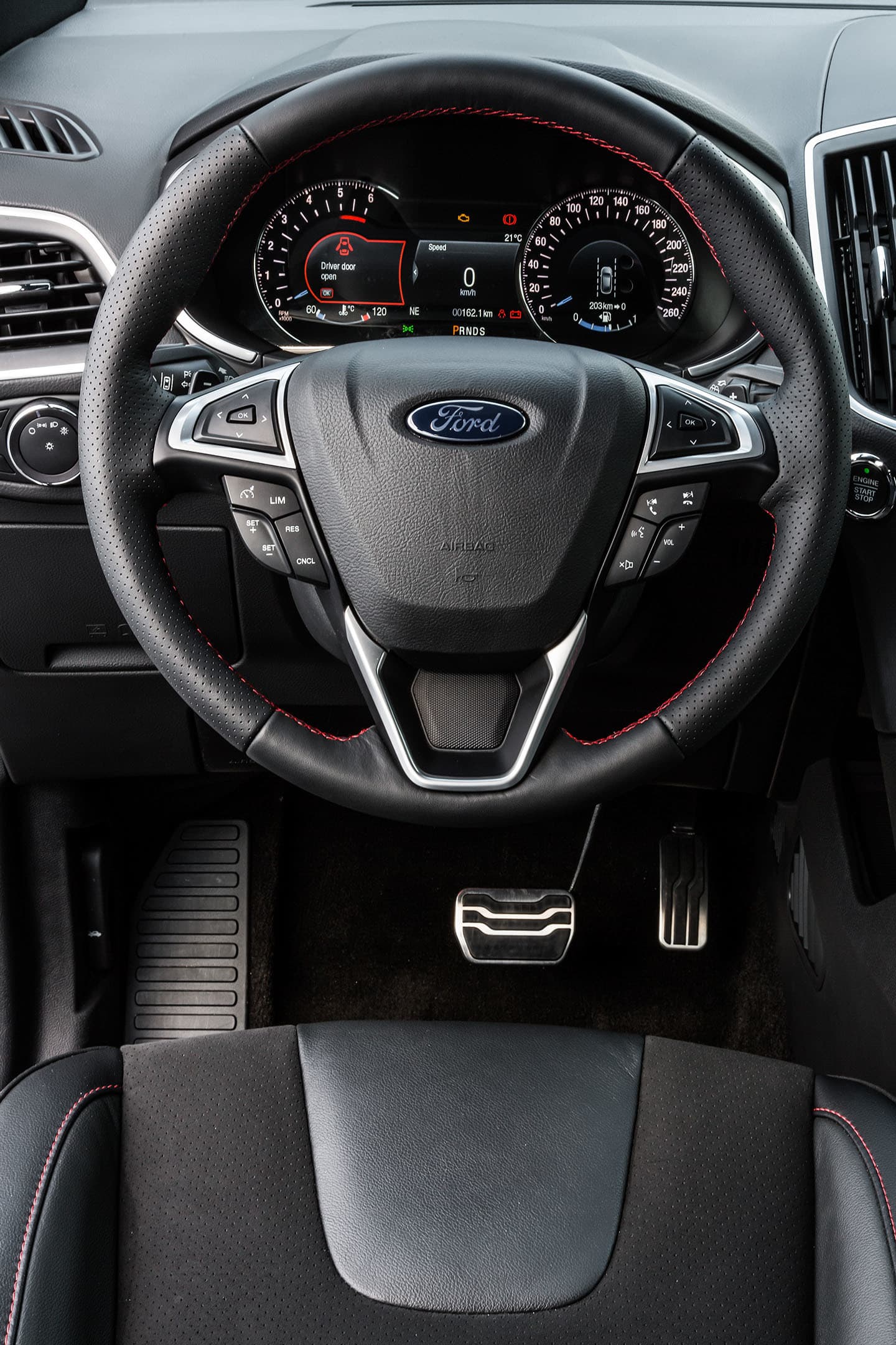 Vista del volante del Ford Edge enfocando emblema y controles.