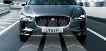 Vista lateral del Jaguar I-PACE rodando con el océano de fondo