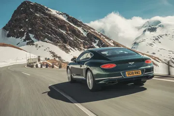 Vista trasera y lateral de un Bentley Continental GT en carretera de montaña