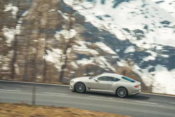 El Bentley Continental GT muestra su perfil lateral en un entorno montañoso.