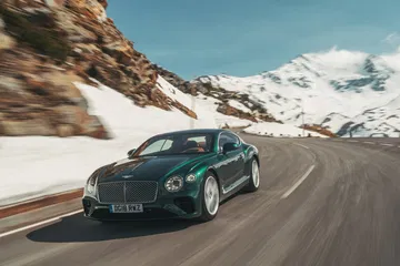 Vista dinámica del Bentley Continental GT en carretera invernal.