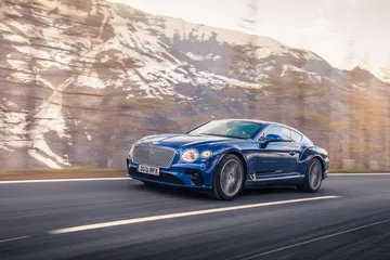 Vista lateral del Bentley Continental GT con montañas al fondo.