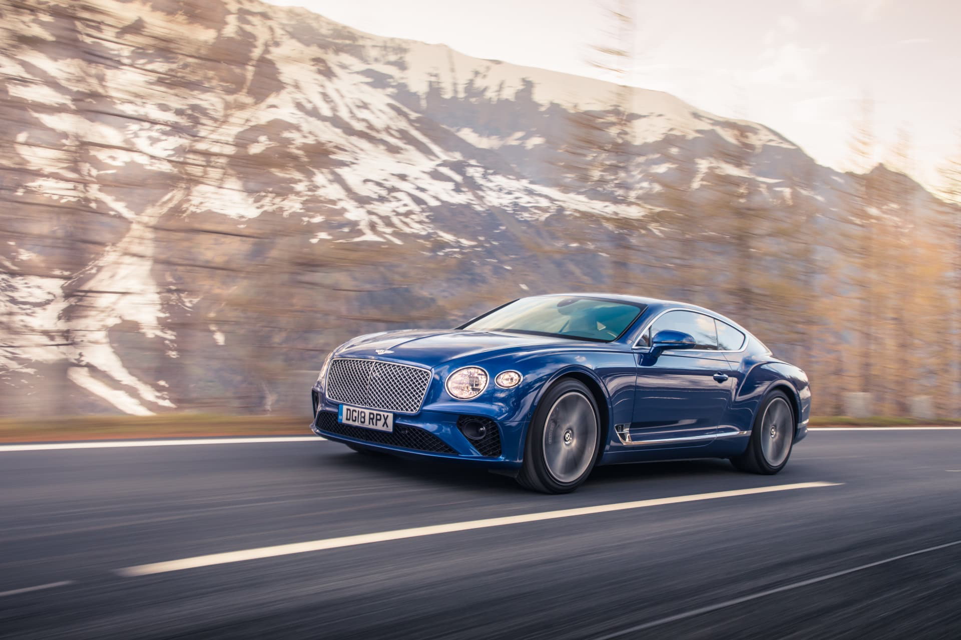 Vista lateral del Bentley Continental GT con montañas al fondo.