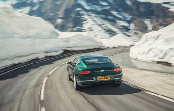 Vista dinámica del Bentley Continental GT rodando en carretera nevada.