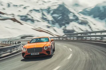 Dinamismo y elegancia en el Bentley Continental GT, capturados en carretera de montaña.