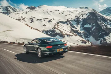 Bentley Continental GT mostrando su elegancia y potencia en carretera de montaña.