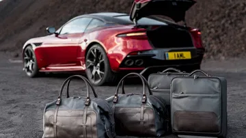 Vista trasera y lateral del DBS Superleggera con maletero abierto y equipaje.
