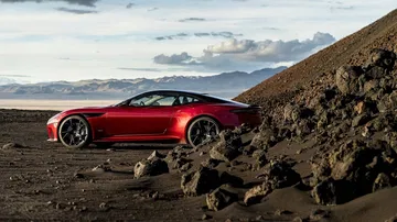 Vista lateral del Aston Martin DBS Superleggera en paisaje montañoso, destacando su silueta.