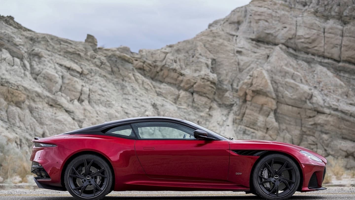 Perfil lateral del Aston Martin DBS Superleggera en rojo ante montañas