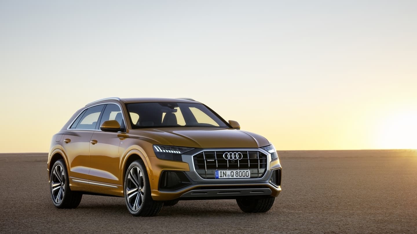 Vista lateral del Audi Q8 en color oro durante la puesta de sol, destacando su diseño elegante.