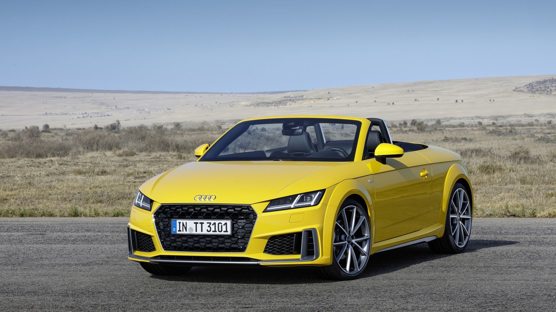 Vista dinámica del Audi TT Roadster en color amarillo, capota descapotable.