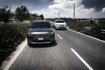 Vista dinámica del Jeep Cherokee en carretera, enfatizando su frontal robusto y diseño lateral.