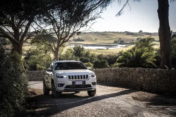 Vista delantera y lateral del Jeep Cherokee en entorno natural.