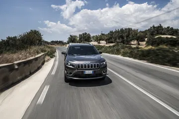 Vista frontal del Jeep Cherokee en carretera, destacando su robusta parrilla.