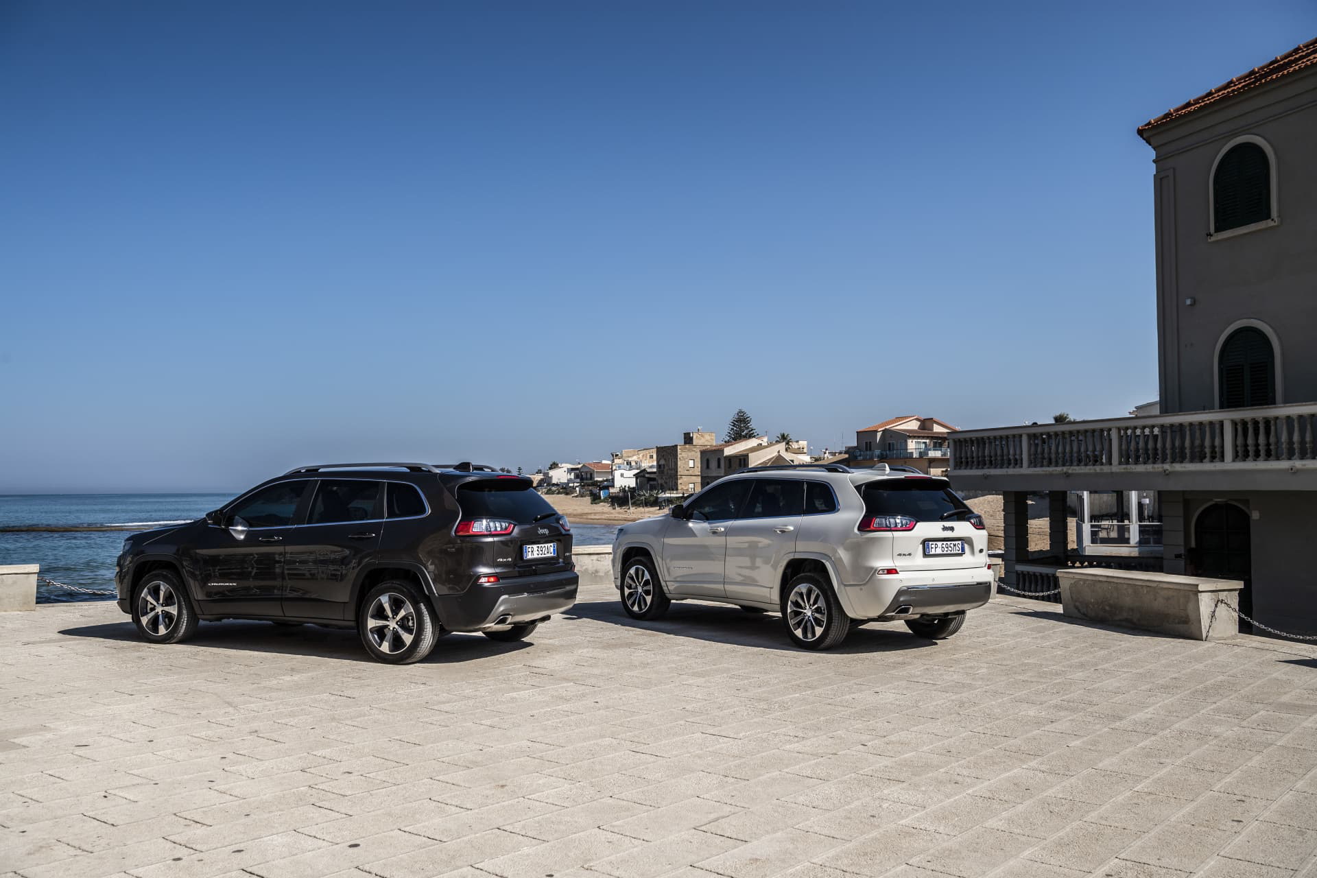 Dos Jeep Cherokee aparcados frente al mar, vista lateral que muestra líneas de diseño.