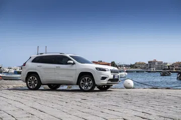 Vista trasera y lateral del Jeep Cherokee en entorno natural, destacando diseño y llantas.