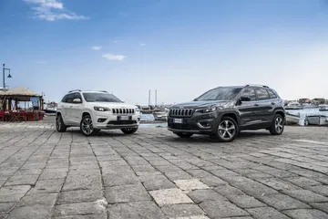 Vista lateral de dos Jeep Cherokee aparcados en un muelle.