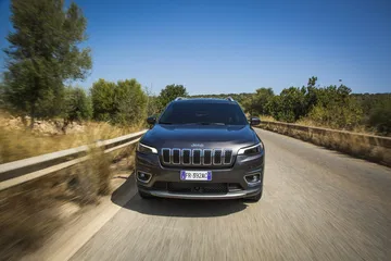 Vista frontal del Jeep Cherokee en movimiento por carretera asfaltada