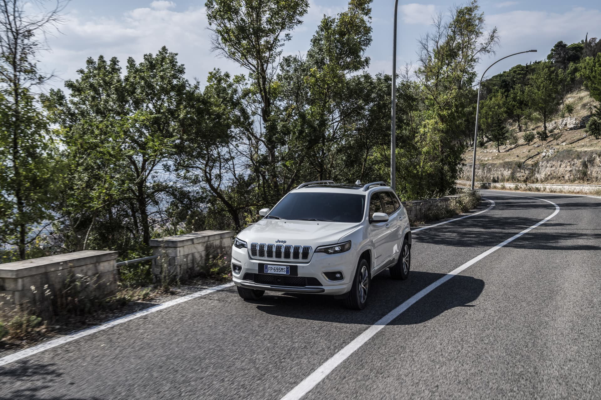 Vista angular delantera del Jeep Cherokee en entorno urbano, destacando su robustez.