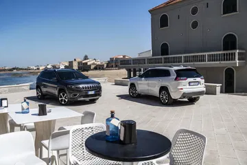 Dos Jeep Cherokee aparcados junto a una terraza con vista al mar.