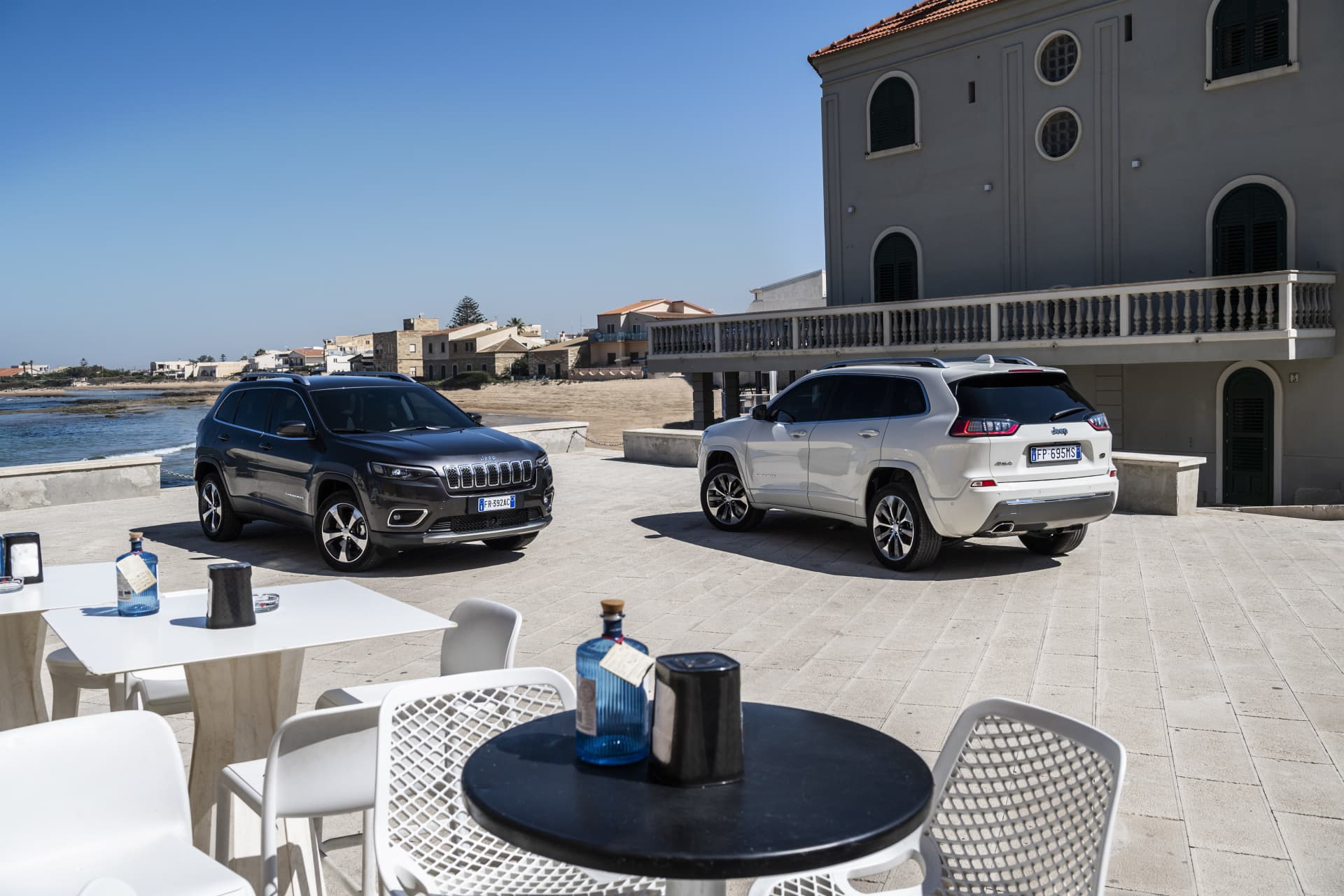 Dos Jeep Cherokee aparcados junto a una terraza con vista al mar.