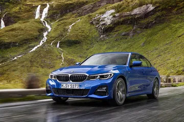 Vista dinámica del BMW Serie 3 en carretera, destacando su diseño frontal y lateral.