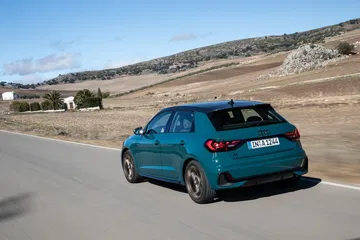 Vista dinámica del Audi A1 en carretera, mostrando su diseño trasero y lateral.