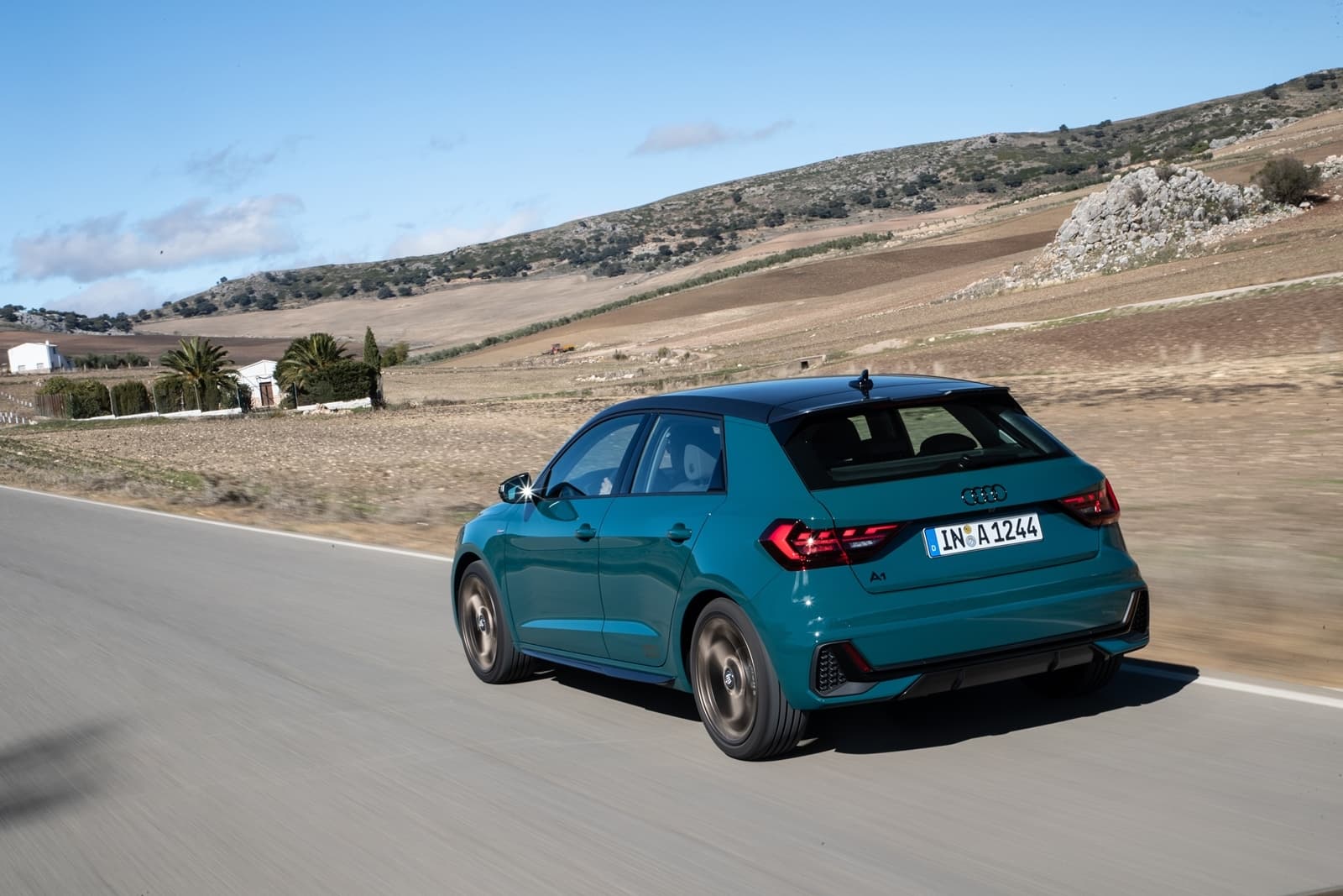 Vista dinámica del Audi A1 en carretera, mostrando su diseño trasero y lateral.