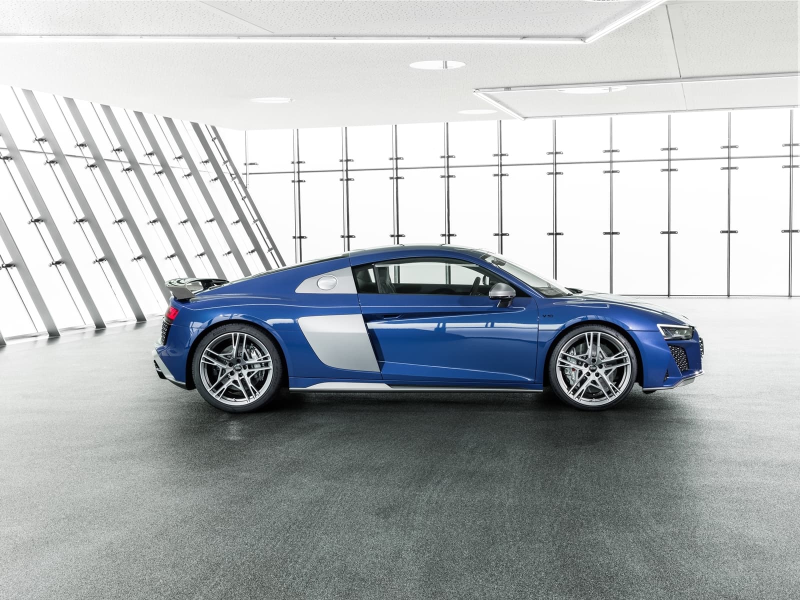 Vista lateral del Audi R8 en tono azul metálico, destacando su línea aerodinámica.