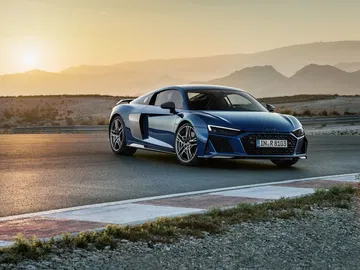 Audi R8 captado al atardecer resaltando su diseño lateral y frontal.