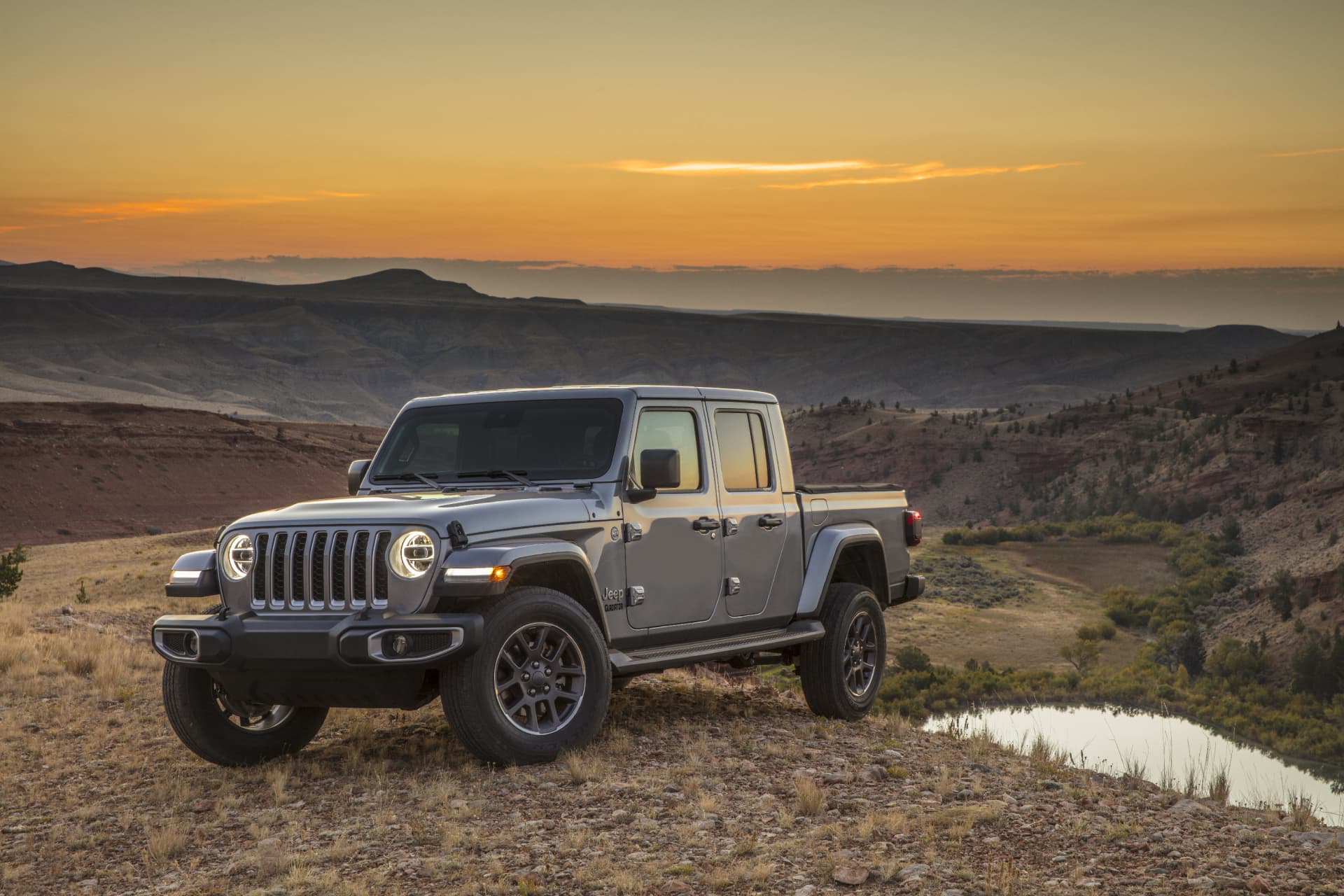 Vista lateral del Jeep Gladiator al atardecer con paisaje de fondo